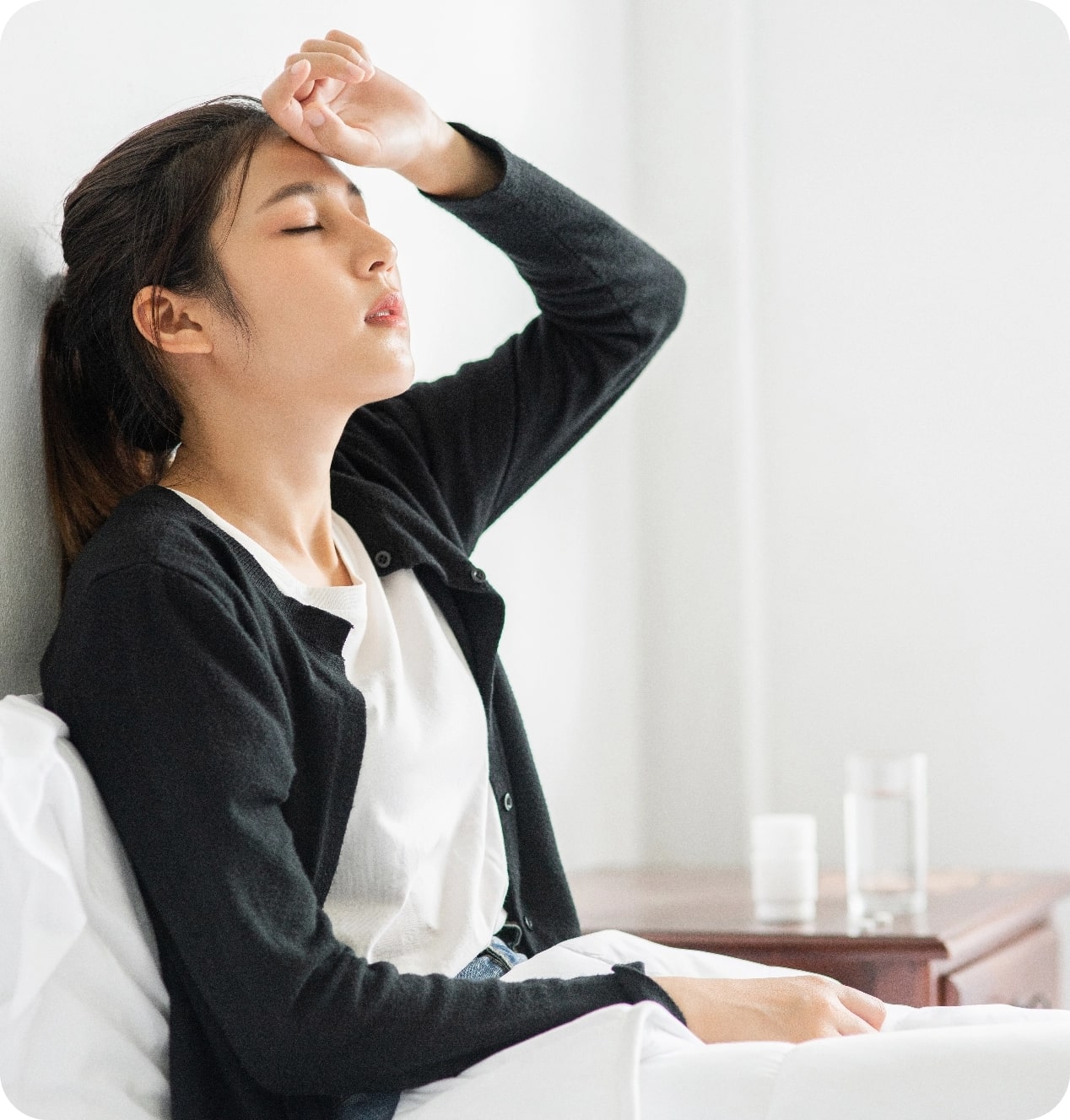 uncomfortable-woman-sits-bed-has-medicine-table@2x-min